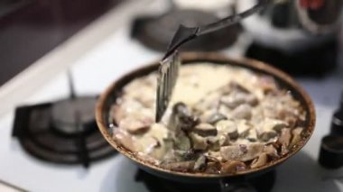 Kızartma tavasında kaymaklı mantar sosu karıştırılıyor. Gaz sobasında pişirilen nefis ev yapımı yemekler. Taze, sağlıklı ve lezzetli mantarlar, akşam yemeği ya da öğle yemeği için mükemmel..