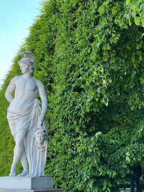 Bu resim, Avusturya 'nın Schonbrunn Sarayı' ndaki açık mavi gökyüzünün altında canlı yeşil yeşilliklerle çerçevelenmiş büyük tarihi bir binanın resimli bir görüntüsünü yakalar. Sahne sükunet ve mimari zarafet yayar..