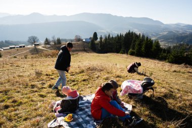 Yamaçta piknik yapan muhteşem dağ manzaralı bir aile, huzurlu bir açık hava günü yakalıyor. Çocuklar oynar ve rahatlar, doğanın güzelliğini kucaklarlar..