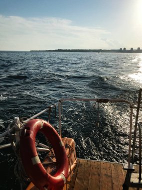 Güneşli bir günde huzurlu bir tekne yolculuğu, engin okyanusu ve uzak kıyı şeridini yakalamak. Güvenlik halkası, sakin suların arasına bir parça deniz güvenliği katıyor..