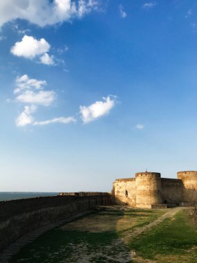 Tarihi bir taş kale güneş ışığıyla yıkanır. Sahne, sükunet ve zamansızlık hissi verir. Bilhorod-Dnistrovskyi kalesi ya da Akkerman Kokot, Ukrayna.