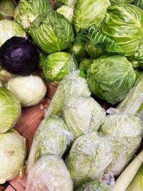 Yerel bir pazarda sergilenen taze yeşil ve mor lahanalardan oluşan canlı bir çeşitlilik. Lahanalar gevşek ve sarmalanmış kafaların karışımı. Tazelik ve çeşitlilik sergiliyorlar..
