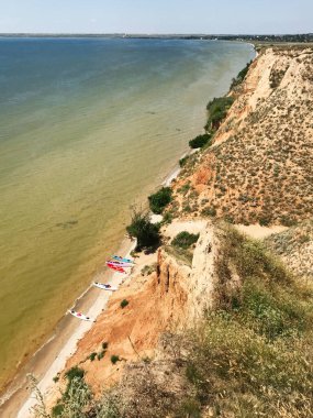 Sakin bir kumsalda dinlenen kanolarla nefes kesici bir sahil manzarası. Engebeli kayalıklar ve sakin su huzurlu ve davetkar bir doğal manzara yaratır. Stanislav Büyük Kanyonu, Ukrayna.