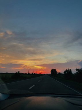Kırsal bir yolda, hareketli bir araçtan hareketli bir günbatımının dinginliğini hissedin. Gezinin ve doğanın güzelliğini gösteren unsurlar..