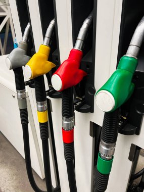Benzin istasyonundaki canlı yakıt pompasının yakın görüntüsü. Görüntü, enerji ve otomotiv endüstrisine odaklanmayı yansıtan, farklı yakıt türlerini temsil eden çeşitli renkler sergiliyor..