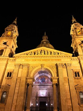 Görüntü, mimari ihtişamını ve karmaşık tasarımını vurgulayarak, tarihi bir katedralin göz kamaştırıcı ve aydınlatıcı dış görünüşünü yansıtıyor. Aziz Stephen Bazilikası, Budapeşte, Macaristan.