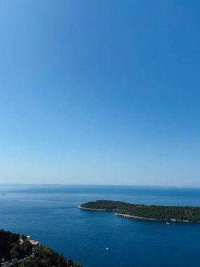 Berrak mavi bir gökyüzü ve yemyeşil ve uzak adalarla çevrili sakin bir deniz manzarası. Huzur ve rahatlama uyandırmak için mükemmel. Lokrum Adası, Dubrovnik, Hırvatistan.
