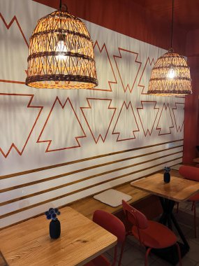 Ilık ve davetkar kafenin içinde örülmüş sepet lambaları, ahşap tablolar ve geometrik duvar kalıpları var. Rahatlama ve sosyal toplanma için samimi ve çağdaş bir atmosfer yaratıyorlar..
