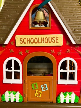 Çocukluk eğitimini sembolize eden, içinde çan ve numaralandırılmış kapı bulunan canlı bir oyuncak okulu. Oyuncu tasarım parlak renkler ve öğrenme temalı bir konsept için mükemmel eğitici unsurlar içerir..