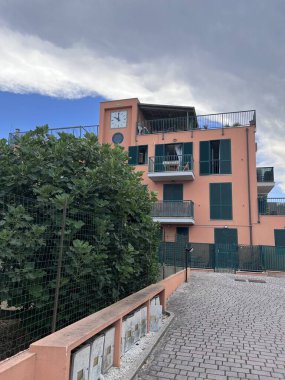 Akdeniz tarzı binalarda canlı pembe duvarlar, yeşil kepenkler ve bir saat kulesi sergileniyor. Yeşilliklerle çevrili bu sahne sükuneti yakalar. Porto Sant 'Elpidio, İtalya.