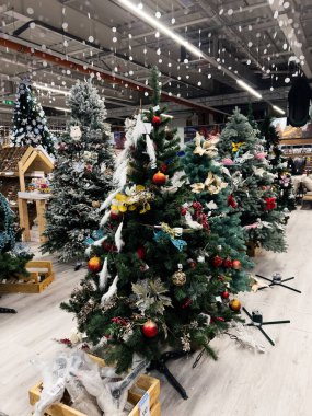 Kyiv, Ukraine - December 02, 2024: A variety of Christmas trees adorned with ornaments and lights, showcased in a retail store setting. The festive atmosphere is highlighted by decorations clipart