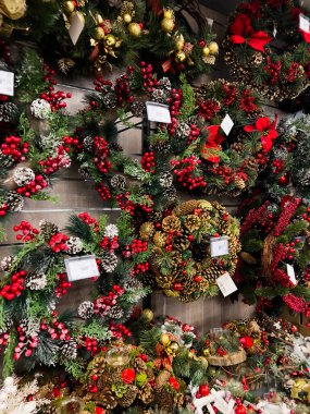 Kyiv, Ukraine - December 02, 2024: A display of beautiful Christmas wreaths adorned with red berries, pine cones, and decorative greenery. clipart