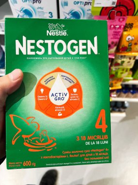 Kyiv, Ukrayna - 02 Aralık 2024: Nestle Nestogen 4 bebek maması kutusunun yakın çekimi bir dükkanda elde tutuldu. Paket, besin faydalarını vurgular ve bebekler için uygundur 