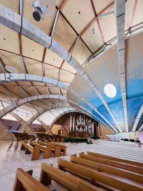 San Giovanni Rotondo, İtalya - 13 Temmuz 2022: Ahşap bankların yer aldığı çağdaş kilise iç mimarisi, etkileyici bir organ ve eşsiz bir şekilde tasarlanmış tavan.. 