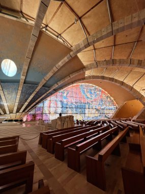 San Giovanni Rotondo, İtalya - 13 Temmuz 2022: Canlı vitray pencereler ve parlak ahşap bankların yer aldığı modern bir kilisenin çarpıcı mimarisi. 