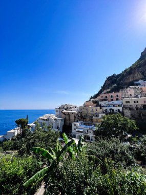 Yamaçta canlı binaların, yemyeşil yeşilliklerin ve çarpıcı okyanus manzaralarının olduğu güzel bir sahil köyü. Rahatlama, seyahat ve parlak mavi gökyüzünün altında Akdeniz cazibesi. Positano, İtalya.
