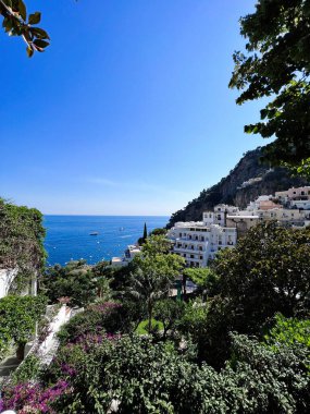 Sahil manzarasında parlak mavi Akdeniz, yemyeşil bahçeler ve büyüleyici yamaç mimarisi yer alır. Seyahat, rahatlama ve doğa temalı projeler için mükemmel. Positano, İtalya.