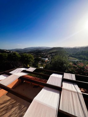 Beautiful hillside landscape with vibrant greenery and a clear sky, featuring cloths drying on wooden supports in the foreground. Captures a serene and rustic atmosphere.  Nocera Umbra, Italy. clipart