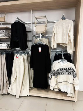 Kyiv, Ukrayna - 18 Aralık 2024: Bir mağazada şık siyah, beyaz ve nötr kıyafetler sergilenmektedir. Bej çantaların yanında modern, zarif örgü ve etekler de var. Işıl ışıl iç mekan sakinliği ve modaya uygun...