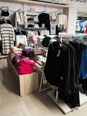 Kyiv, Ukrayna - 18 Aralık 2024: Bir perakende giyim mağazası, masa ve raflarda katlanmış süveter ve giysi sergiliyor, müşteri sergisi için stil ve renge göre düzenleniyor. Mağazada çantalar, sonbahar ve kış giysileri var..