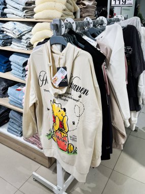 Kyiv, Ukraine - December 18, 2024: Hoodies featuring a popular cartoon character displayed in a clothing store. They contain colorful illustrations and textual elements enhancing their appeal in a casual setting surrounded by other apparel. clipart