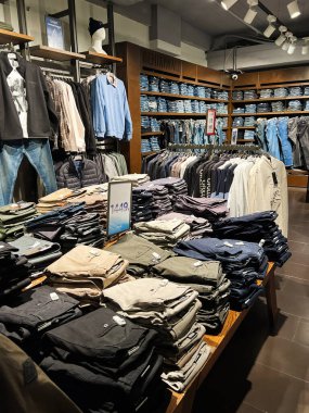 Kyiv, Ukrayna - 18 Aralık 2024: İyi aydınlatılmış kotlar, pantolonlar ve gömlekler sergileniyor. Modern bir perakende tasarımı temiz organizasyonu vurguluyor ve çok çeşitli giyim seçenekleriyle müşterileri davet ediyor..