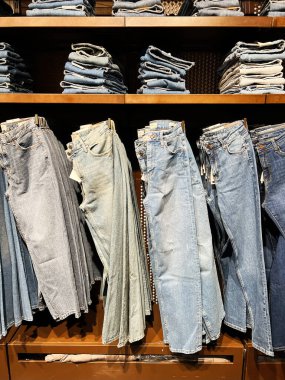 Kyiv, Ukrayna - 18 Aralık 2024: Giysi perakendecisinde mavi ve soluk kot pantolon sergilenen iyi düzenlenmiş raflar.