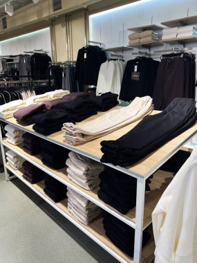 Kyiv, Ukrayna - 18 Aralık 2024: Bir giyim mağazasının raflarında düzgünce katlanmış kazak ve pantolon sergilenen fotoğraf. Alışveriş ilhamı için düzenli ve davetkâr bir mağaza düzenini vurgular.