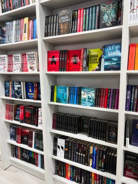 Kyiv, Ukrayna - 18 Aralık 2024: Kitaplıklar çeşitli renkli kitaplar, türler ve başlıklar sergiliyor, okuyucular ve edebiyat tutkunları için organize ve modern bir kitapçıda davet edici bir atmosfer sunuyor.