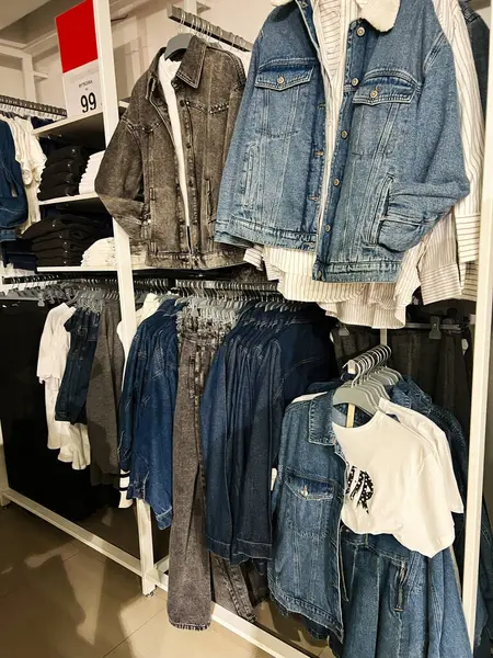 Kyiv, Ukrayna - 18 Aralık 2024: Modern bir perakende mağazası ortamında Denim ceketleri, gömlekler ve üst raflarda sergilendi. Moda trendlerini, kıyafet alışverişini veya tanıtım ve ticari amaçlar için iç tasarımları sergilemek için ideal.