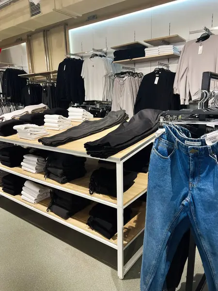 Kyiv, Ukrayna - 18 Aralık 2024: Gömlekler ve pantolonlar da dahil olmak üzere düzenli katlanmış günlük kıyafetlerin yer aldığı bir perakende mağazası. Organize ve davetkar, bu sahne çağdaş moda ve perakende sunumunu temsil ediyor.