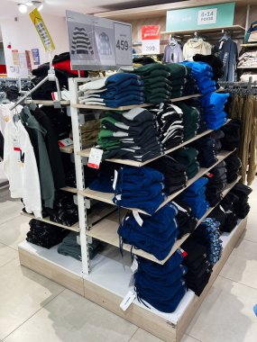 Kyiv, Ukrayna - 18 Aralık 2024: Çocuklar için düzgünce katlanmış süveter ve giysi yığınlarının yer aldığı bir perakende sergisi. Görüntü modern bir mağaza ortamında düzenli ve temiz bir giyim bölümünü gösteriyor..