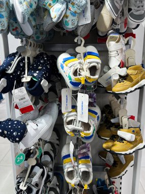 Kyiv, Ukraine - December 18, 2024: Vibrant collection of children's footwear in various sizes and designs, organized on shelves within a shop. Includes sneakers, boots, and slippers in diverse colors, highlighting retail presentation and product vari clipart