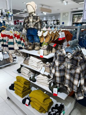 Kyiv, Ukraine - December 18, 2024: Clothing store display featuring trendy children's wear, including hats, plaid shirts, and cozy sweaters, with organized shelves showing boots and folded items for a neat shopping experience. clipart