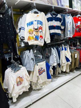 Kyiv, Ukrayna - 18 Aralık 2024: Karakter temalı ve çizgili tasarımlar da dahil olmak üzere çeşitli renkli çocuk tişörtlerinin sergilenmesi, bir perakende mağazasında düzgünce asılı durması.