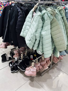 A collection of winter jackets and boots are on display in a retail fashion store. The carefully arranged garments and shoes showcase seasonal styles, emphasizing comfort, durability, and modern aesthetics for winter wear. clipart