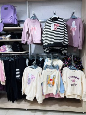 Kyiv, Ukrayna - 18 Aralık 2024: Bir perakende mağazasındaki raflarda ve askılarda çeşitli şık eşofman üstleri ve sırt çantaları sergileniyor, gençler ve genç yetişkinler için gündelik, gençlik modası ve modaya uygun giyim tercihleri vurgulanıyor. 