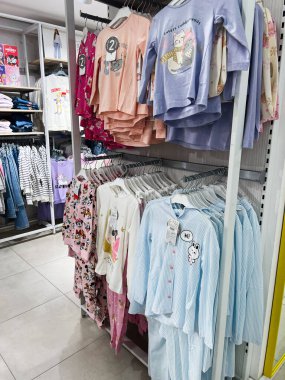 Kyiv, Ukrayna - 18 Aralık 2024: Bir mağaza giyim reyonundaki raflarda asılı şirin ve renkli çocuk pijamaları seçimi. Pijamalar eğlenceli desenler ve tasarımlar içeriyor. Aileler için neşeli bir alışveriş ortamı yaratıyor..