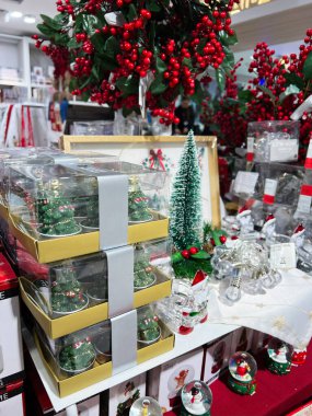 Kyiv, Ukrayna - 18 Aralık 2024: Canlı Noel süsleri sergilenmekte, yemyeşil ağaçlar, şenlikli ambalajlar ve dekorasyonlar sergilenmekte, parlak kırmızı böğürtlenler ve parlak aksanla sıcak ve neşeli bir bayram alışveriş atmosferi yaratmaktadır.