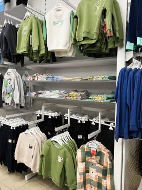 Kyiv, Ukrayna - 18 Aralık 2024: Perakende ortamda raflarda sergilenen süveterler, gömlekler ve pantolonlar da dahil olmak üzere çocuk kıyafetlerinin düzenli bir düzenlemesi. Gündelik giysiler için çok çeşitli renk ve tasarımlar sergilenmektedir..