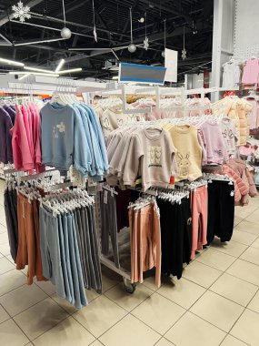 Kyiv, Ukrayna - 18 Aralık 2024: Bir mağazada raflara dizilmiş süveterler, pantolonlar ve ceketlerden oluşan renkli çocuk kıyafetleri. Çevre aydınlık, düzenli ve görsel olarak çekici bir ortam sergiliyor.. 