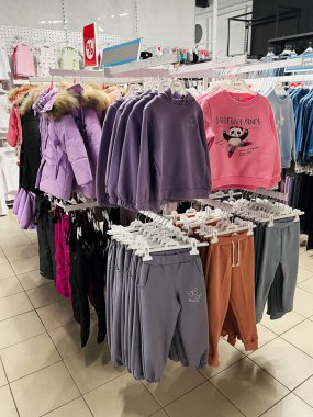 Kyiv, Ukraine - December 18, 2024: Display of various children's clothing including outfits and jackets arranged neatly in a retail store setting. Colorful designs and appealing patterns target young audiences and emphasize warmth and comfort. clipart