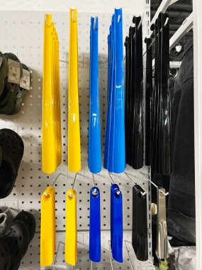 Kyiv, Ukraine - December 18, 2024: Various vibrant yellow, blue, black, and metallic shoe horns arranged neatly on display in a retail shop. Ideal image for themes about shopping, retail products, or organizational items. clipart