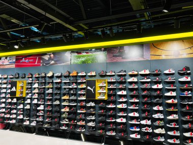 Kyiv, Ukraine - December 18, 2024: A neat and organized wall display of diverse sneakers inside a brightly lit shoe store. clipart