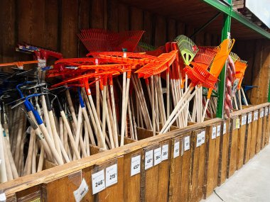 Kyiv, Ukrayna - 03 Ocak 2025: Hırdavatçıda ahşap saplı parlak renkli bahçe tırmıkları koleksiyonu. Açık alan ve bahçe işleri için etkili araçlar.