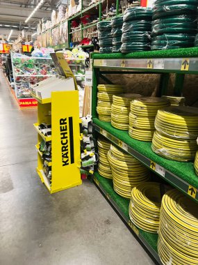 Kyiv, Ukraine - January 03, 2025: Display of coiled garden hoses on store shelves alongside gardening equipment in a well-lit retail interior with visible signage and organized layout.  clipart