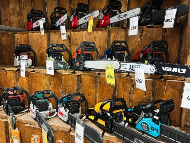 Kyiv, Ukraine - January 03, 2025: Various models of chainsaws exhibited on wooden shelves in a store, showcasing their variety and functionality. Perfect image for themes of tool shopping, equipment, and professional-grade machinery. clipart