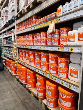 Kyiv, Ukraine - January 03, 2025: Rows of orange paint buckets and other products neatly arranged on shelves in a store. The scene portrays an interior of a hardware or paint store with organized product inventory. clipart