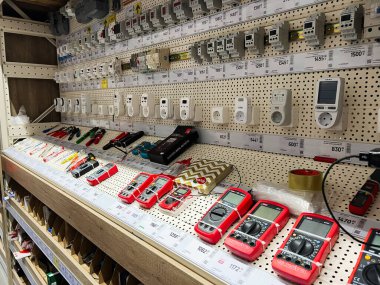 Kyiv, Ukraine - January 03, 2025: An organized shelf showcasing a variety of electronic tools and measurement devices commonly used in electrical and technical work, displayed in a hardware store setting. clipart