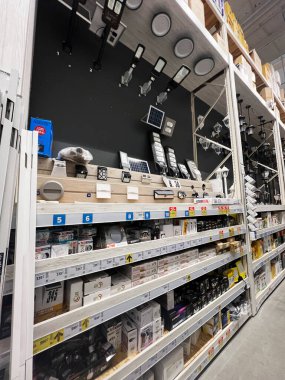 Kyiv, Ukraine - January 03, 2025: Shelves in a retail store displaying a variety of lighting fixtures and accessories, including solar panels and LED modules, arranged neatly for customer selection in a hardware-themed shopping environment.  clipart